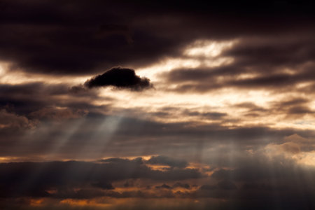 Sunbeams coming through gray clouds before the storm