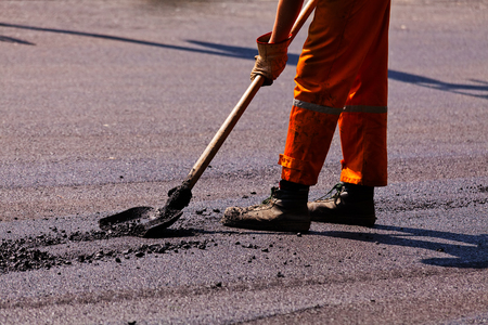 Worker on asphalting the road, note shallow depth of fieldの写真素材