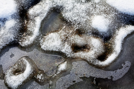 View of ice and melting snow on frozen groundの写真素材