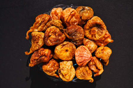 Top view of dry figs in glass bowl, on black tableの写真素材