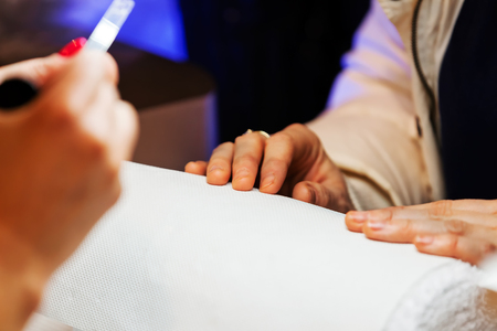 Young beautiful woman in a nail salon receiving a manicure by a professional beauticianの写真素材