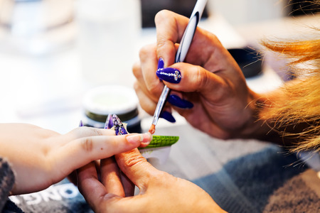 Young beautiful woman in a nail salon receiving a manicure by a professional beauticianの写真素材