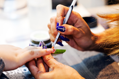 Young beautiful woman in a nail salon receiving a manicure by a professional beautician の写真素材