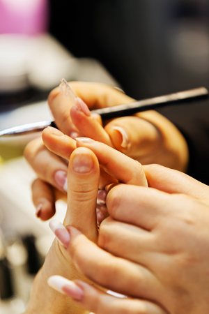 Young beautiful woman in a nail salon receiving a manicure by a professional beauticianの写真素材
