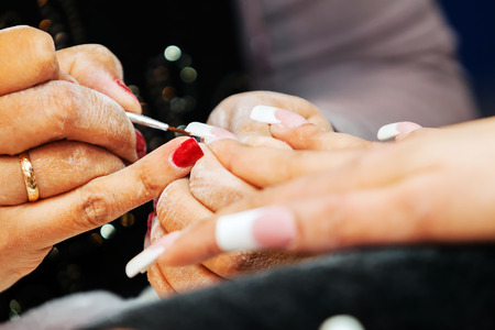Young beautiful woman in a nail salon receiving a manicure by a professional beauticianの写真素材