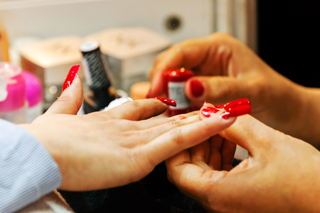 Young beautiful woman in a nail salon receiving a manicure by a professional beauticianの写真素材