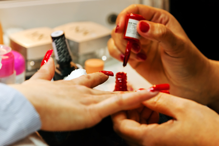 Young beautiful woman in a nail salon receiving a manicure by a professional beauticianの写真素材