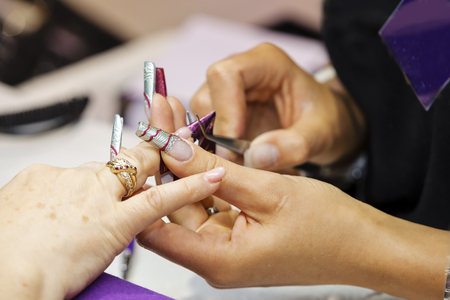 Woman is getting manicure treatment in beauty salon;  note shallow depth of fieldの写真素材