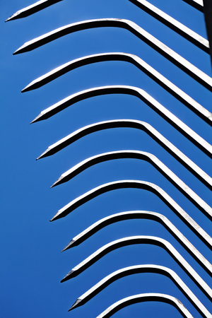 Sharp metal fence pikes against blue skyの写真素材