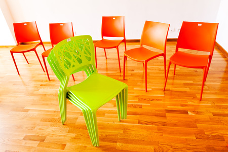 Green stacked chairs with red chairs around them, front viewの写真素材