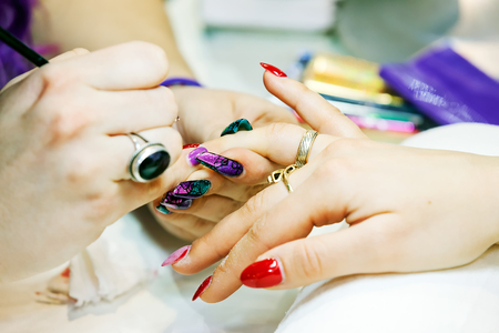Young beautiful woman in a nail salon receiving a manicure by a professional beauticianの写真素材