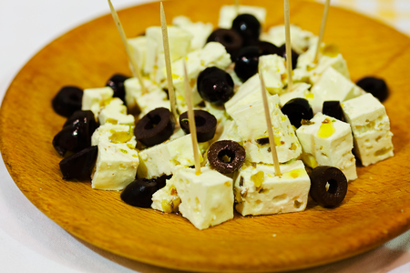 Goat's cheese with black olives on wooden plateの写真素材