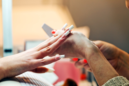 Young beautiful woman in a nail salon receiving a manicure by a professional beauticianの写真素材