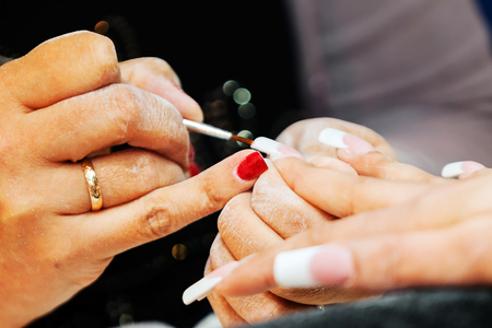 Young beautiful woman in a nail salon receiving a manicure by a professional beautician の写真素材