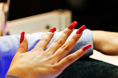 Young beautiful woman in a nail salon receiving a manicure by a professional beauticianの写真素材