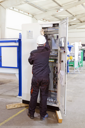Man worker checking advanced industrial control panel in the production hallの写真素材
