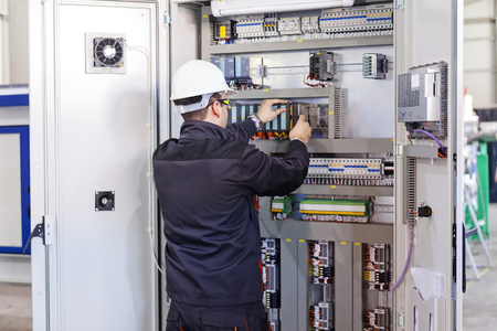 Man worker checking advanced industrial control panel; note shallow depth of fieldの写真素材