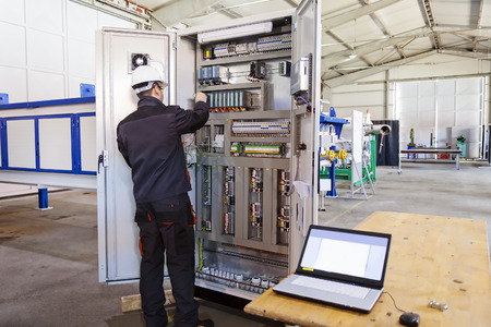 Man worker checking advanced industrial control panel in the production hall の写真素材