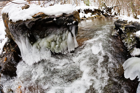 Frozen rock in mountain stream, on winter dayの写真素材