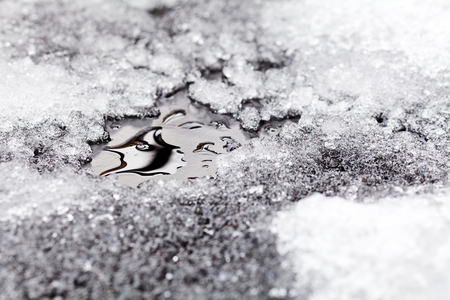 View of melting snow in small puddle on asphaltの写真素材