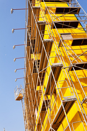 yellow protective tarpaulins and scaffolding on a buildingの写真素材