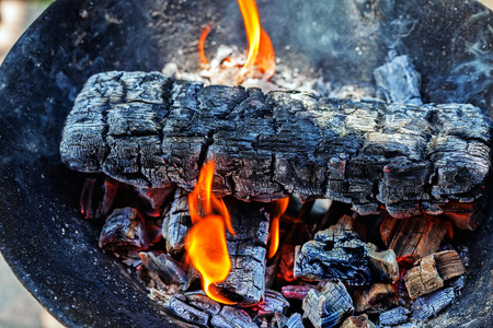 Wood burning with flames, ash and smoke in a barbecueの写真素材