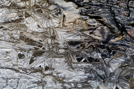 Frozen ground and small puddle on winter morningの写真素材