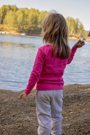 The girl throws stones into the lakeの写真素材