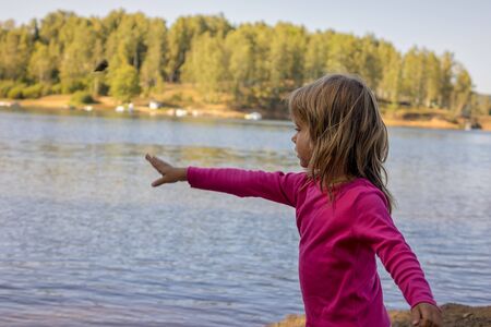 The girl throws stones into the lakeの写真素材