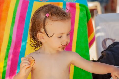baby eating a donut on the beach, note shallow depth of fieldの写真素材