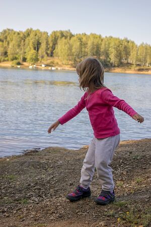 The girl throws stones into the lakeの写真素材