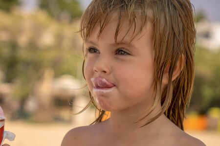 The child eats ice cream in the corn on the beachの写真素材