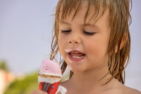 The child eats ice cream in the corn on the beachの写真素材