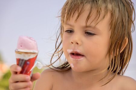 The child eats ice cream in the corn on the beachの写真素材