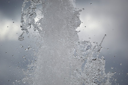 Drops of water in the water jet of the fountain in the foreground