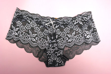 black lace lingerie on a pink background, closeup of photo