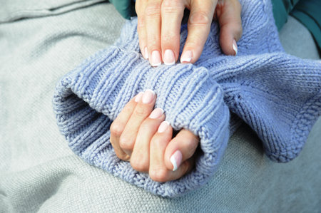 Female hands in a knitted sweater on a gray background close-upの写真素材