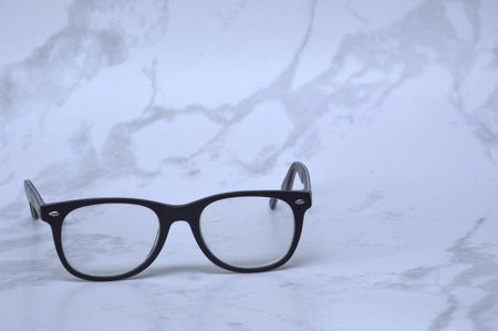 Black eye glasses on a white marble background with copy space for text