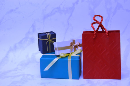 Colorful gift boxes and red paper bag on a white marble backgroundの写真素材