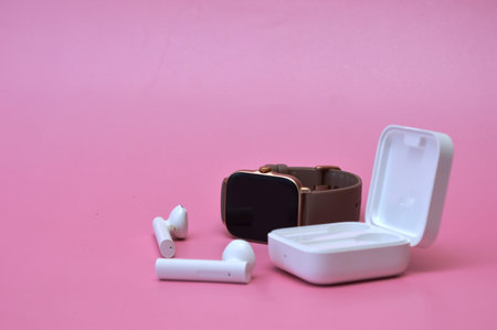 smart watch and earphones on a pink background, close-up