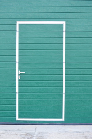 Green wall with a white door, close-up, vertical photoの写真素材