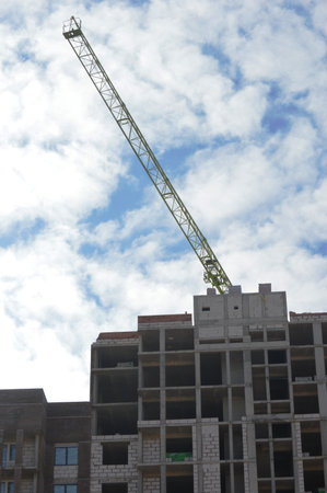 Crane and building under construction against blue sky with white clouds.の写真素材