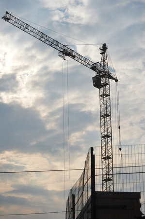 Silhouette of construction crane against blue sky with white clouds.の写真素材