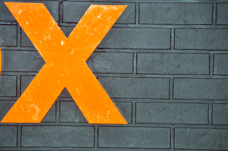 Orange cross sign on brick wall background, closeup of photo.の写真素材