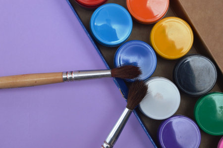 Paint brushes and paints in a box on a purple background.の写真素材