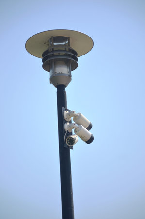security camera and light pole in the blue sky, closeup of photo