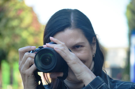 Female photographer with camera in the park. Focus on the camera.
