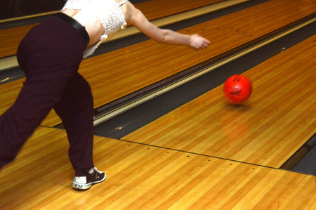 Bowling ball in motion on the bowling alley with woman in backgroundの写真素材