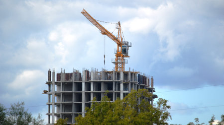 Construction site with cranes and building under construction against blue sky.