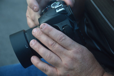 Male hands holding a DSLR camera. Focus on the lens.の写真素材